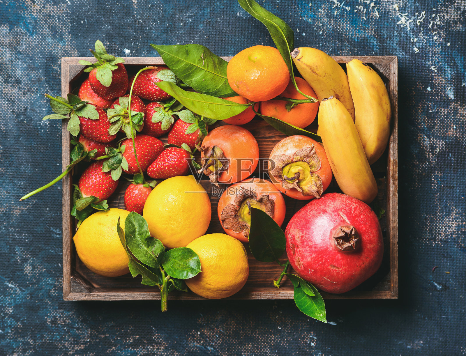 橘子，柠檬，石榴，香蕉，草莓和柿子装在木盒里照片摄影图片