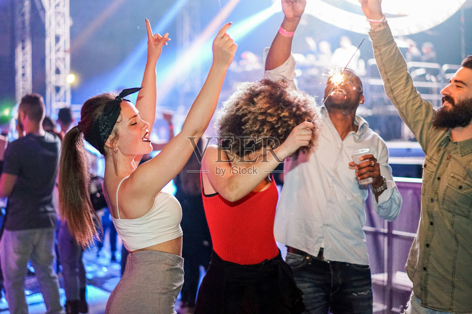 年轻的朋友跳舞在夜店节日活动派对与dj在背景-快乐的人有乐趣在迪斯科-夜生活的概念-未过滤照片与软焦点左女孩的脸照片摄影图片