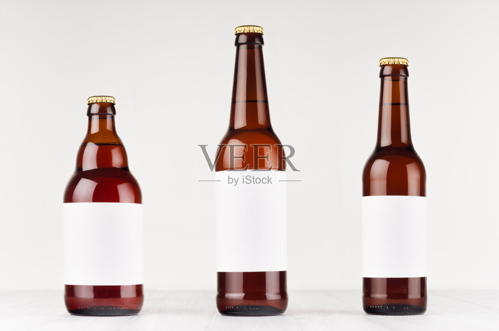 棕色啤酒瓶收集不同类型与空白白色标签在白色木板，模拟。照片摄影图片