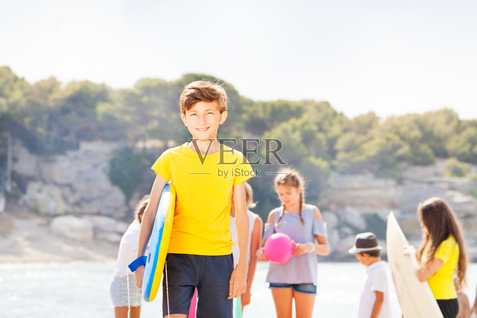 男孩抱着滑板站在沙滩上照片摄影图片