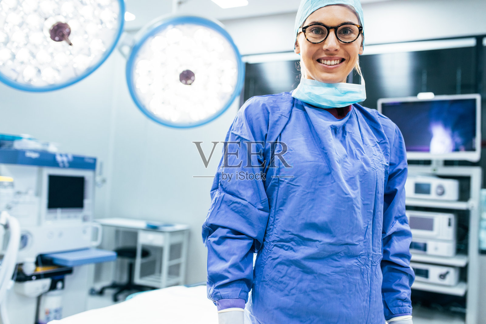 微笑的女外科医生穿着手术制服在手术室照片摄影图片