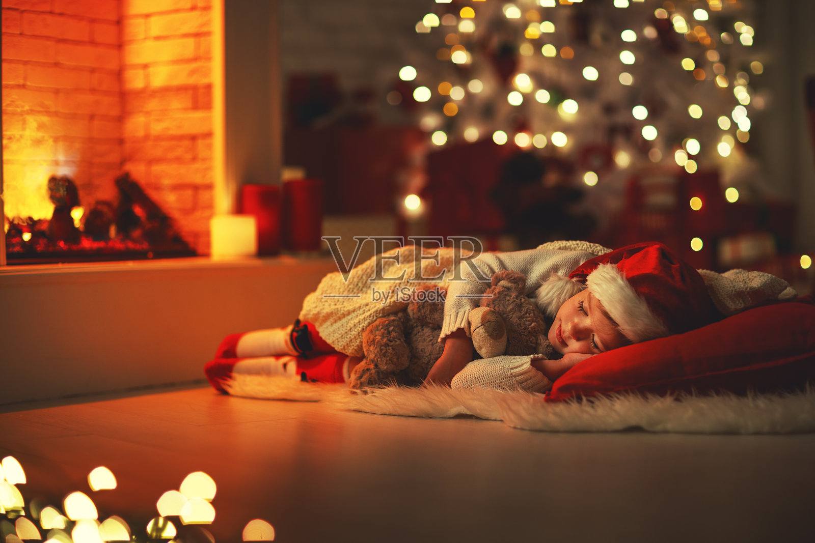 圣诞节前夕，一个小女孩在圣诞树旁睡着了照片摄影图片