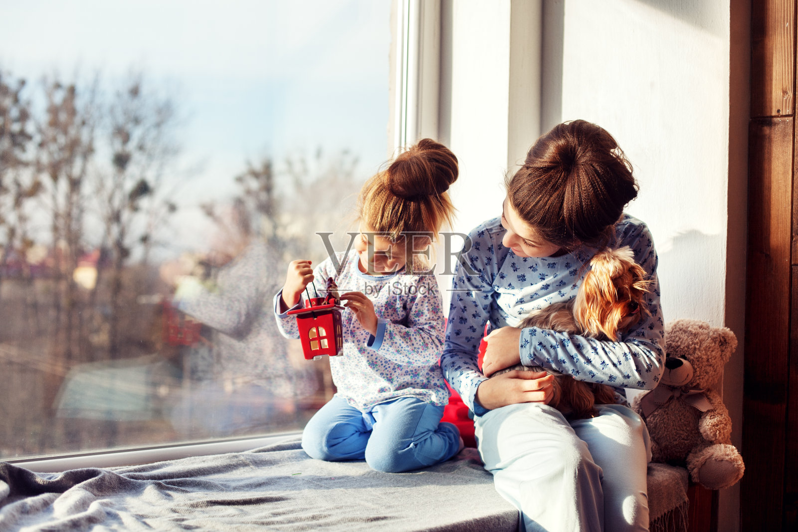 姐妹们和小狗坐在窗台上。圣诞节的概念照片摄影图片