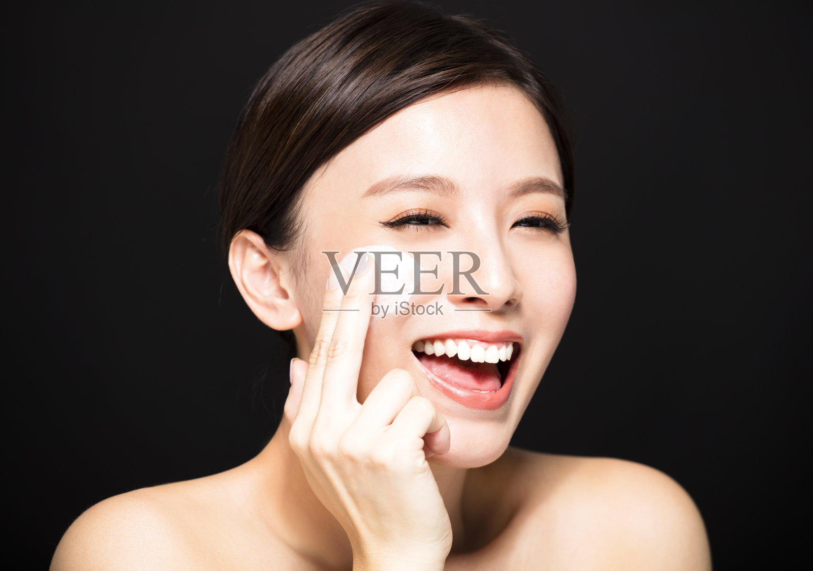 快乐的女人在脸上涂护肤霜照片摄影图片