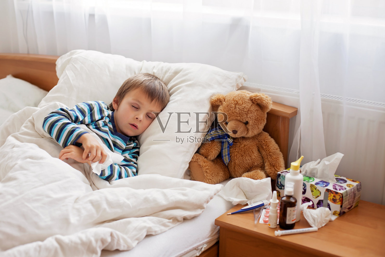 生病的小男孩发烧躺在床上休息照片摄影图片