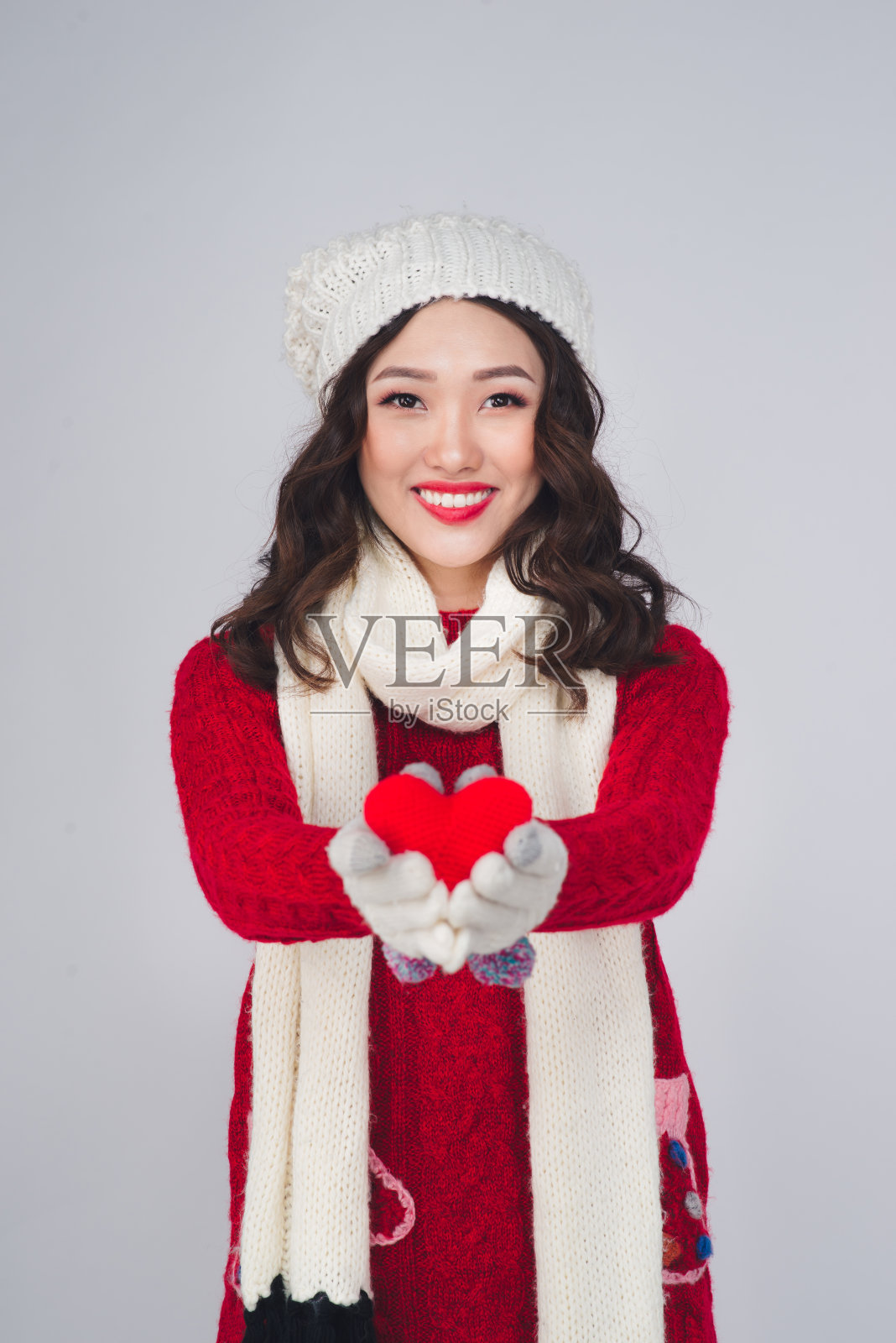 圣诞冬天幸福概念。亚洲妇女穿着冬季服装，呈心形。照片摄影图片