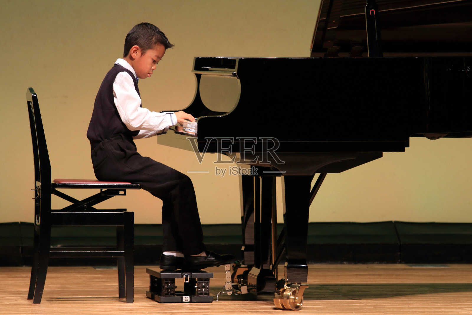 日本男孩在舞台上弹钢琴(小学二年级)照片摄影图片
