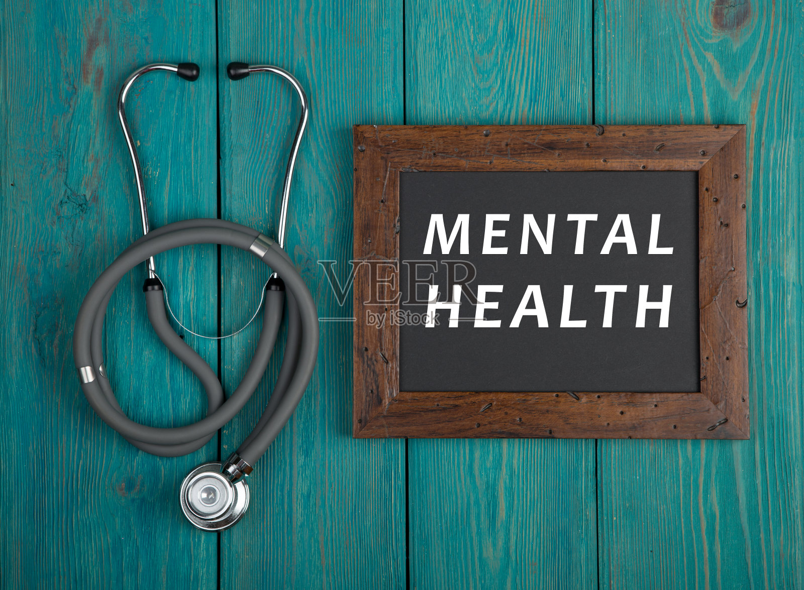 黑板上写着“心理健康”，听诊器以蓝色木制为背景照片摄影图片
