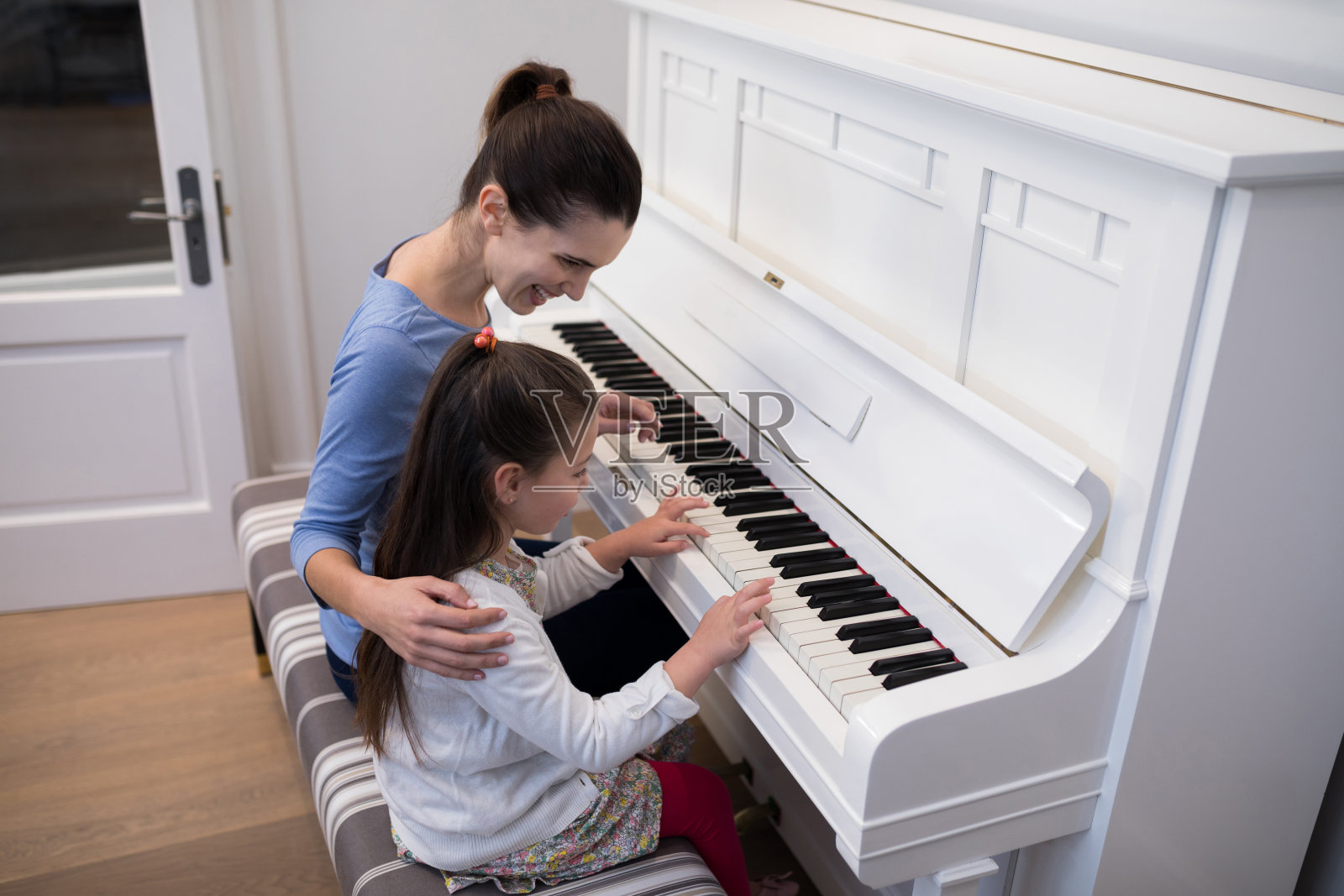 母亲帮助女儿弹钢琴照片摄影图片