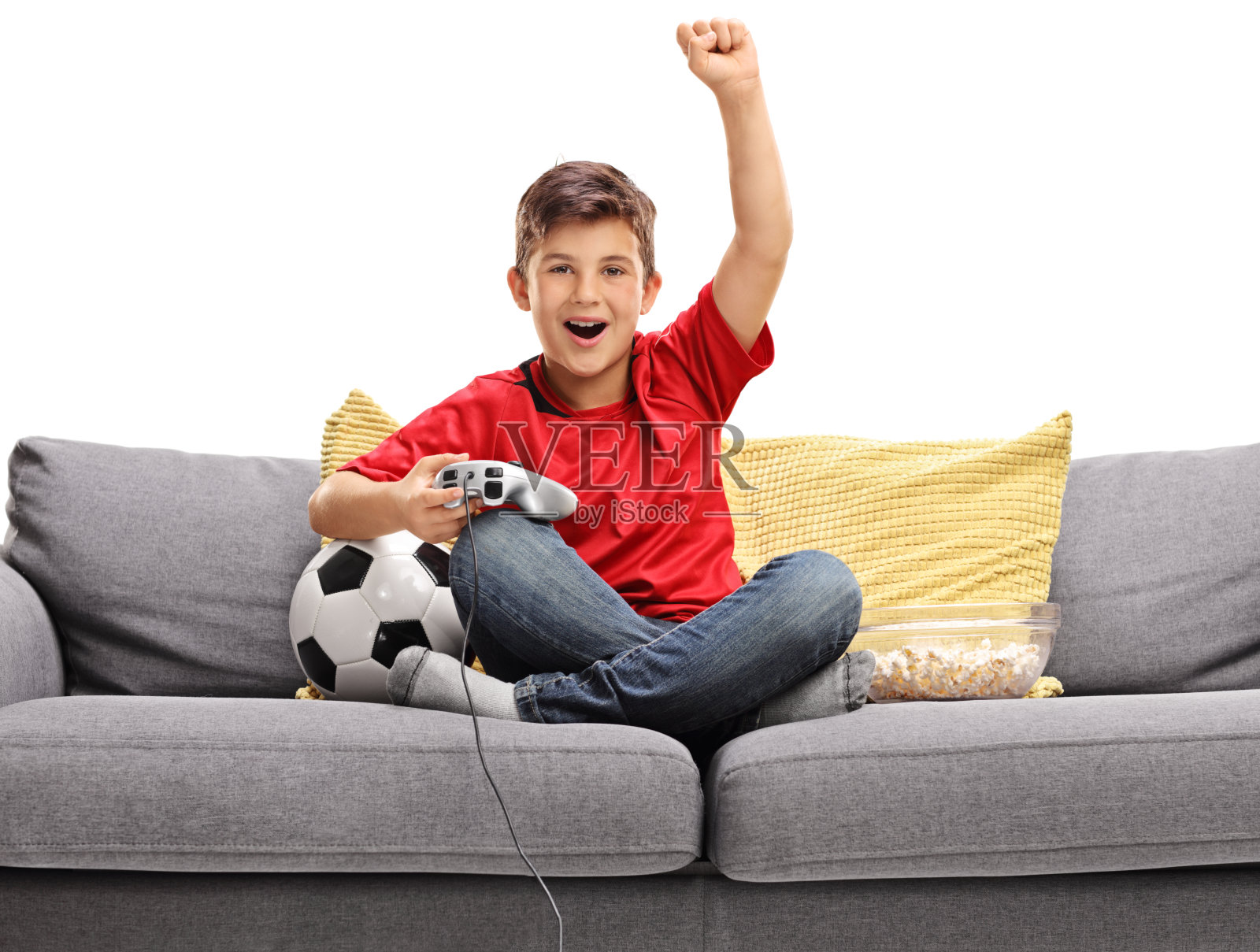 快乐的小男孩坐在沙发上玩足球电子游戏照片摄影图片