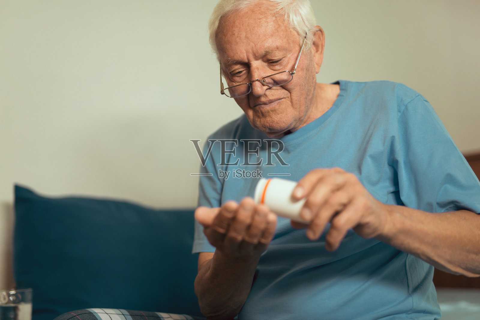 坐在家里的床上吃药的老人照片摄影图片