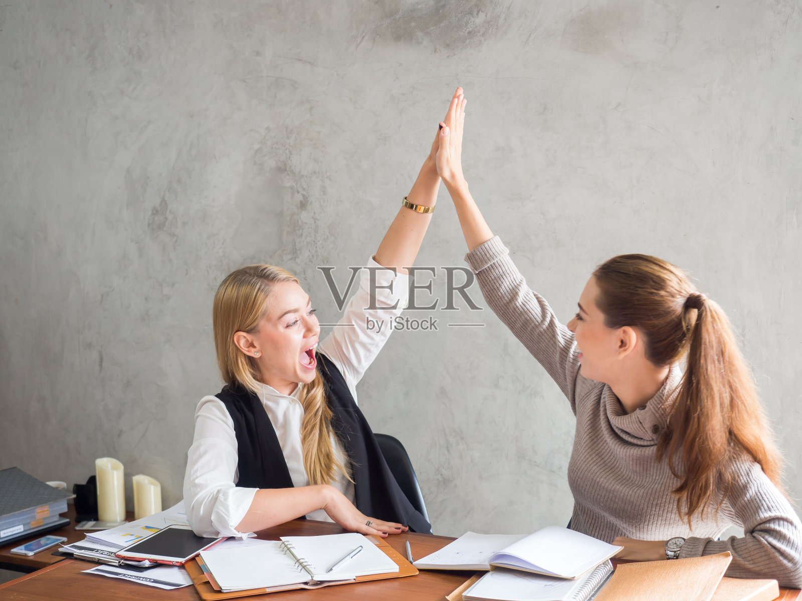 两个女商人微笑着举起手，感觉周五很快乐，完成了工作，成功/成就的工作在办公室的概念照片摄影图片