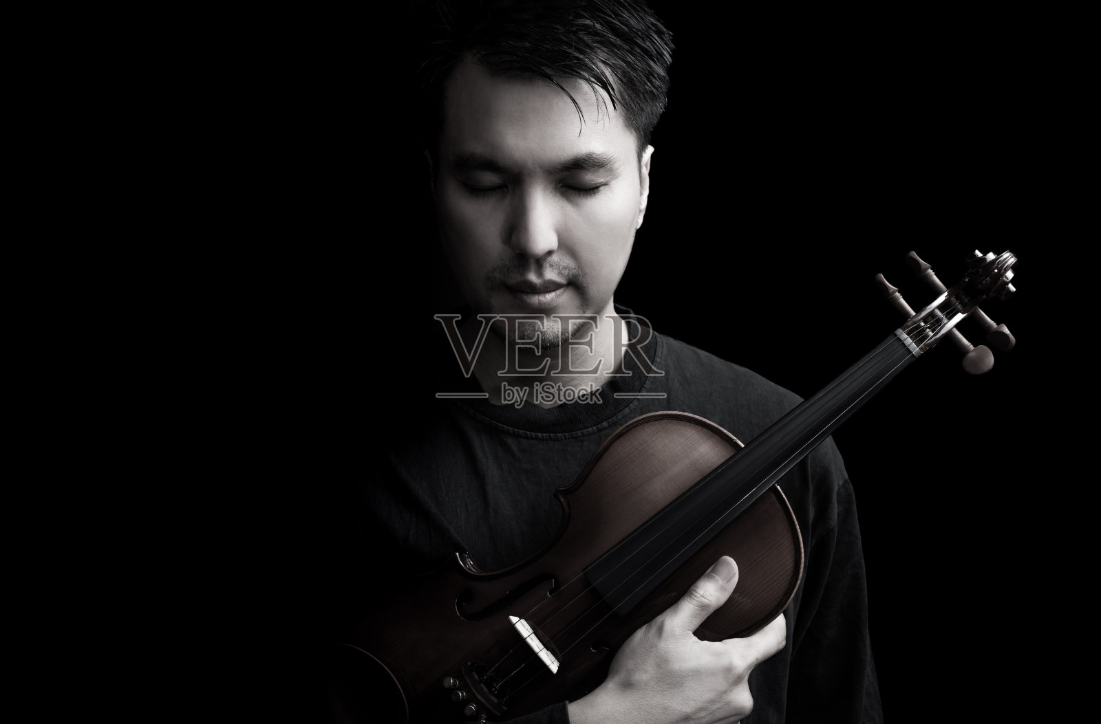 情感肖像的亚洲英俊的音乐家摆上小提琴，孤立在黑色照片摄影图片