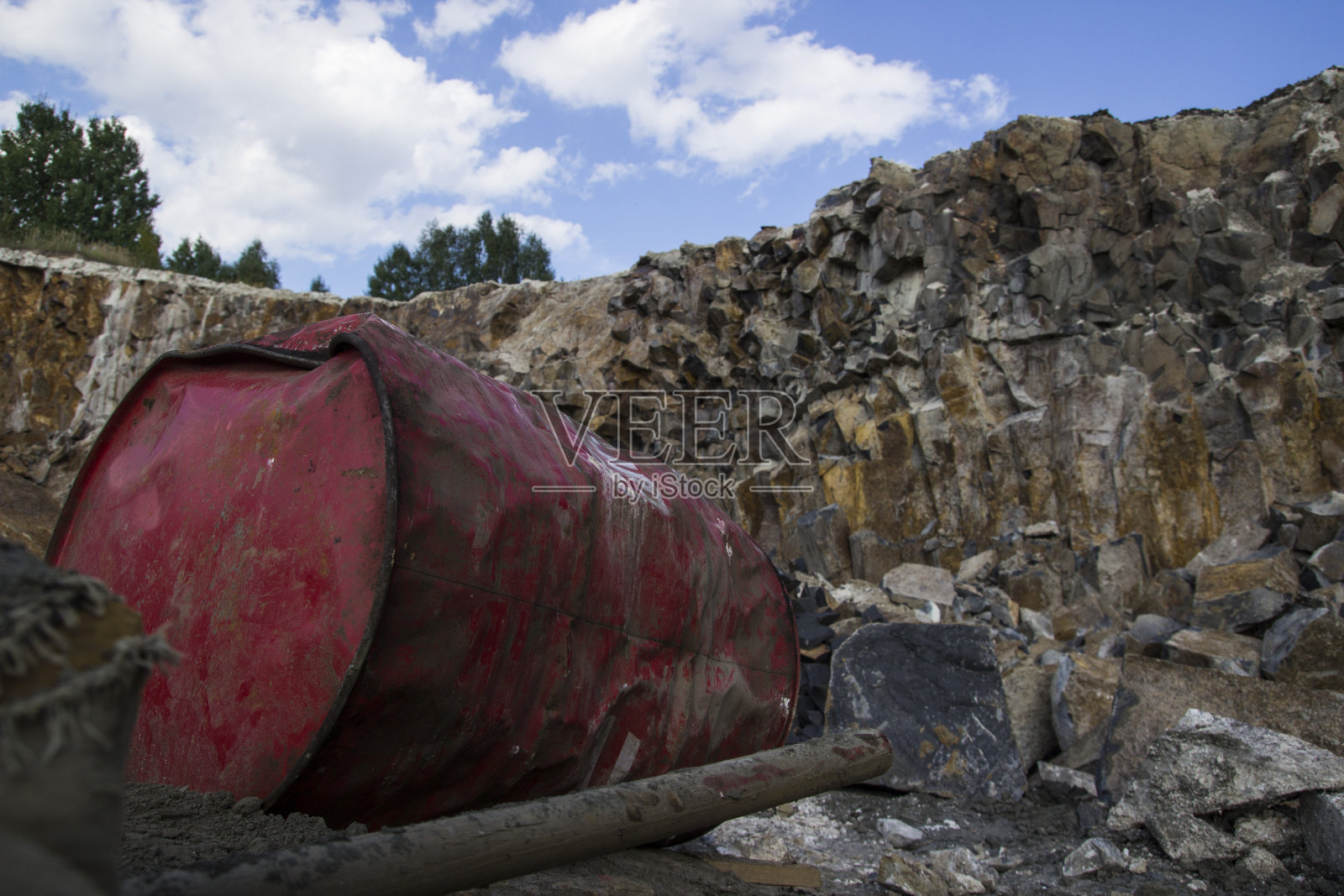 玄武岩柱。红色金属桶。石头开挖。重工业照片摄影图片