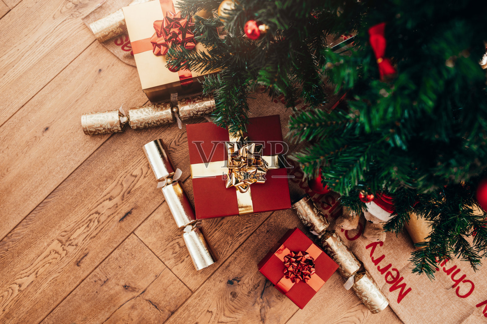 圣诞树旁放着礼盒和圣诞爆竹。照片摄影图片