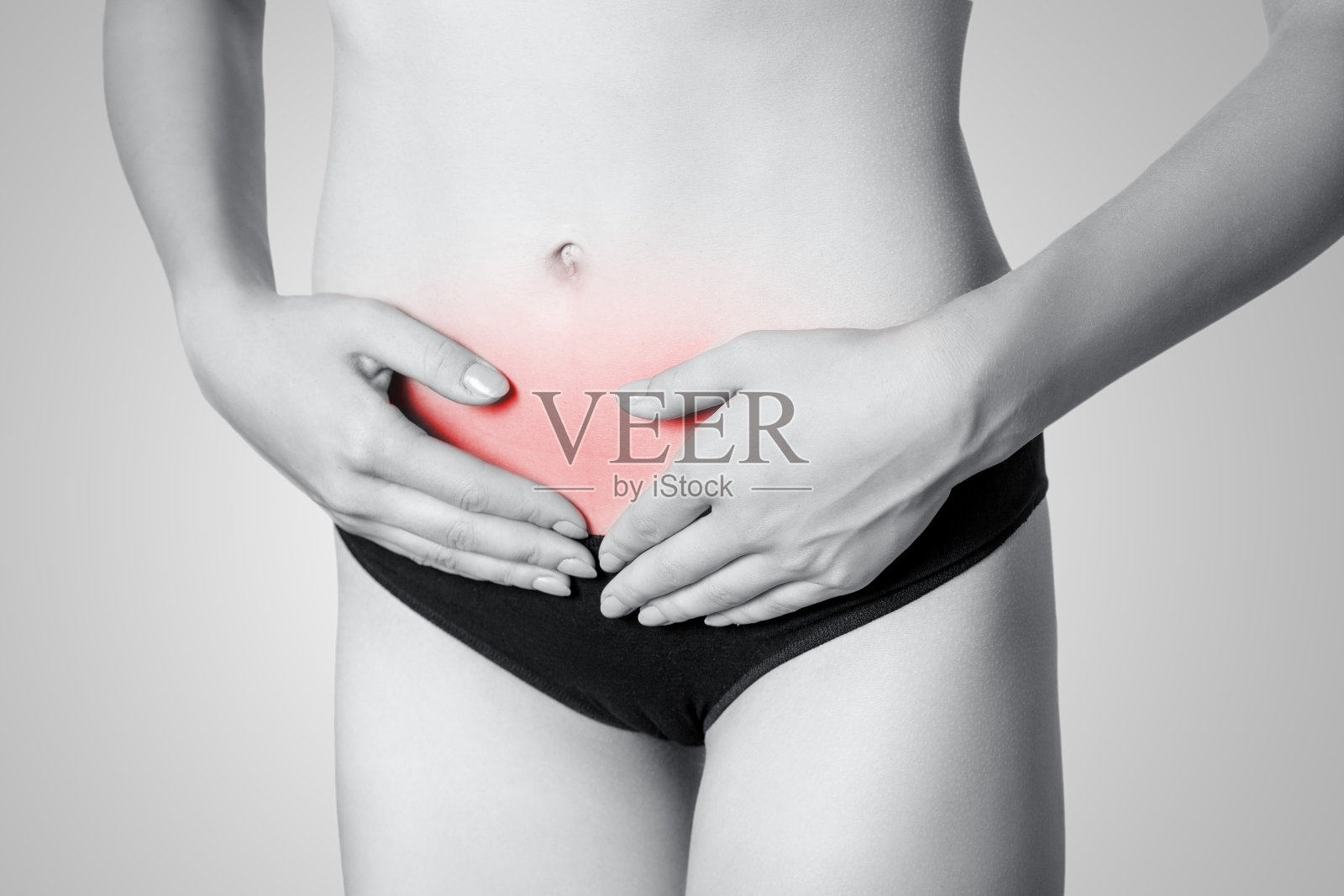 一个年轻女性的胃痛或消化或周期的特写在灰色背景。照片摄影图片