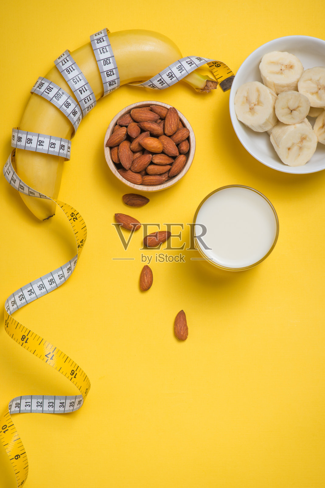 香蕉，牛奶和杏仁，用卷尺在黄色的背景上复印照片摄影图片
