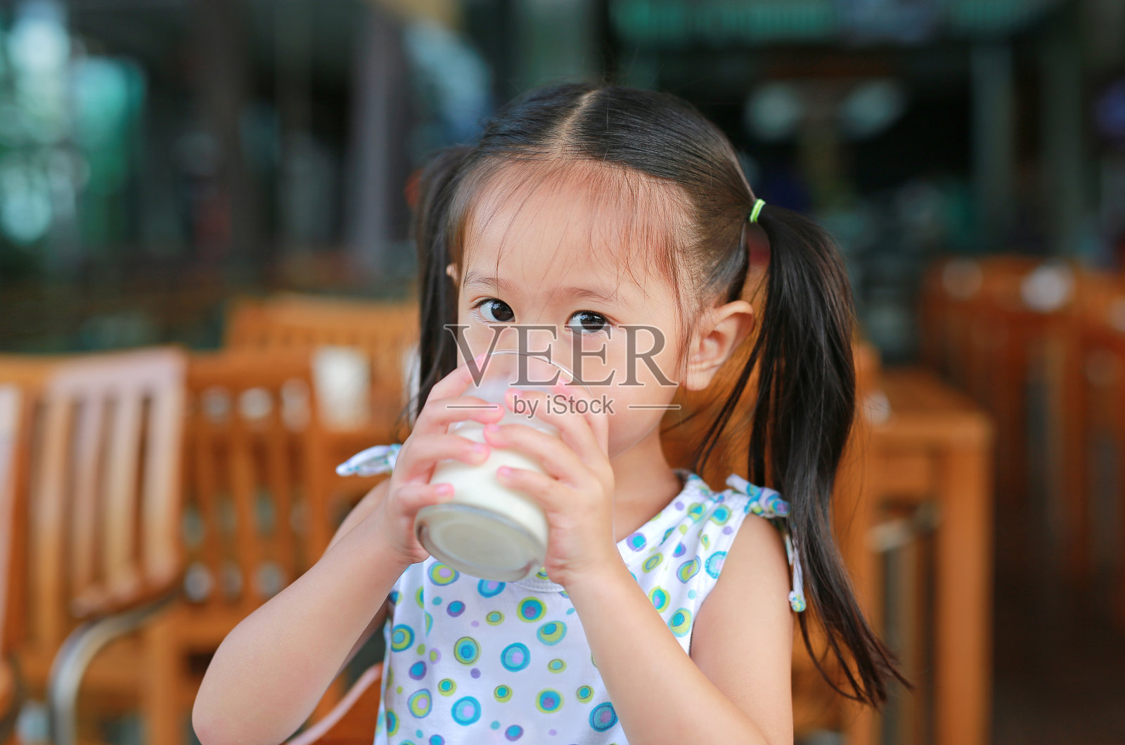 亚洲小女孩早上在餐厅喝牛奶。照片摄影图片