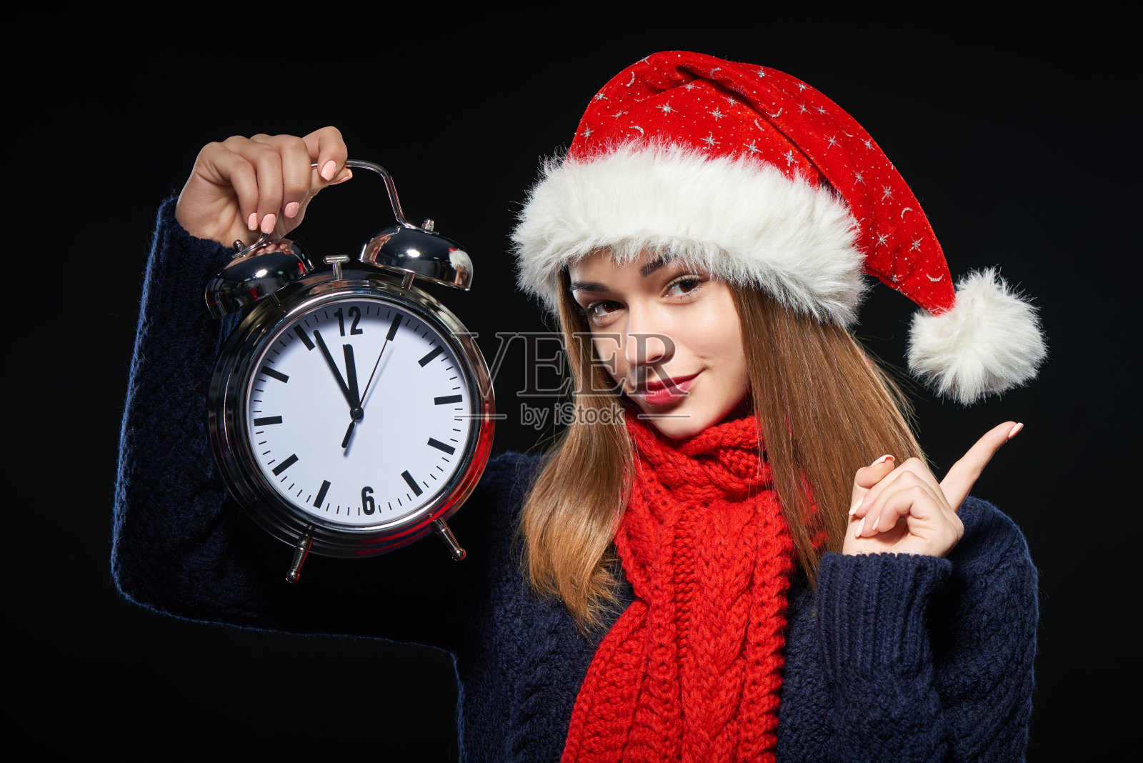 戴着圣诞帽和时钟的惊讶女孩照片摄影图片