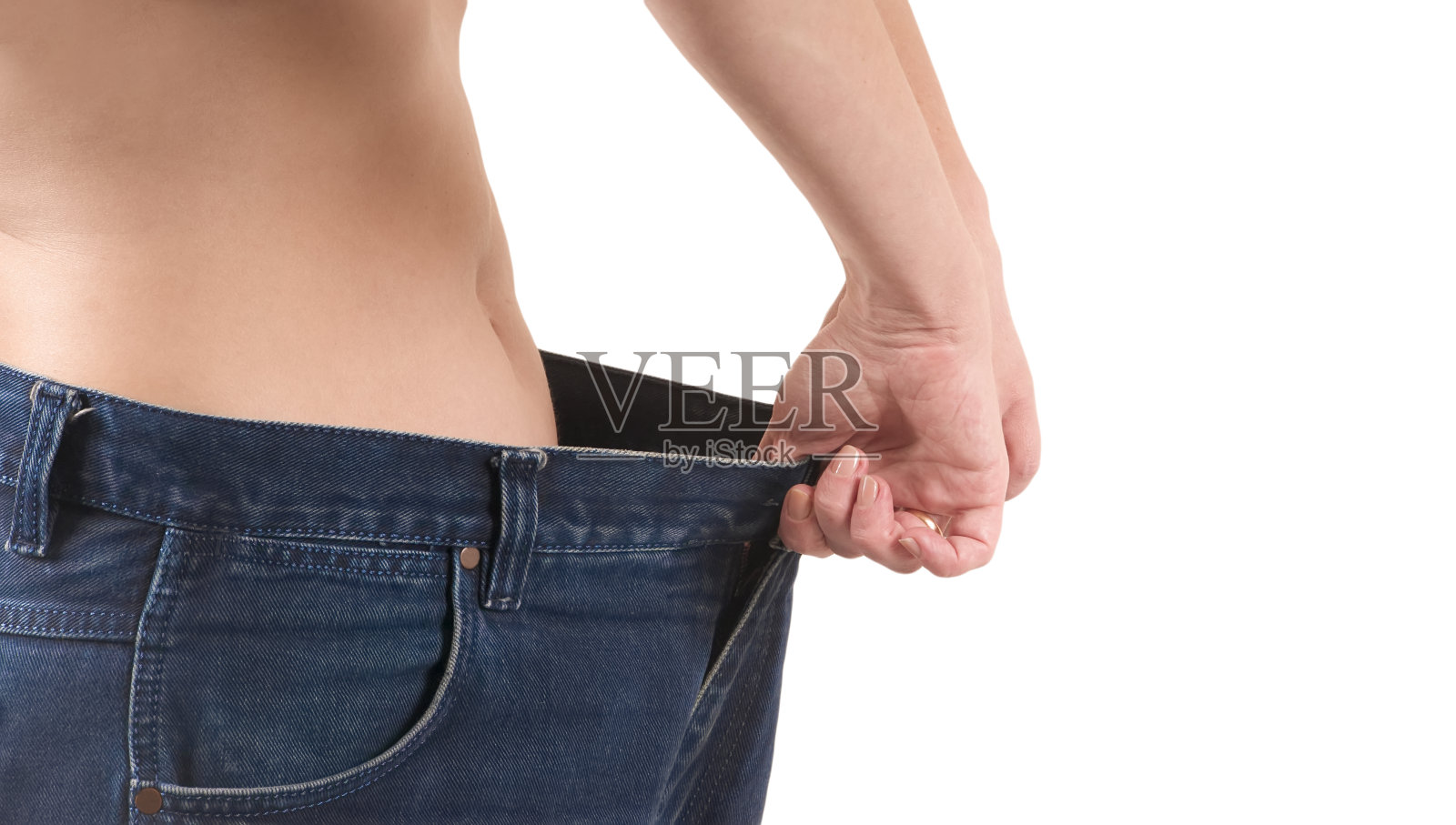 一位女士穿了一条旧的大裤子以示减肥。减肥的概念照片摄影图片