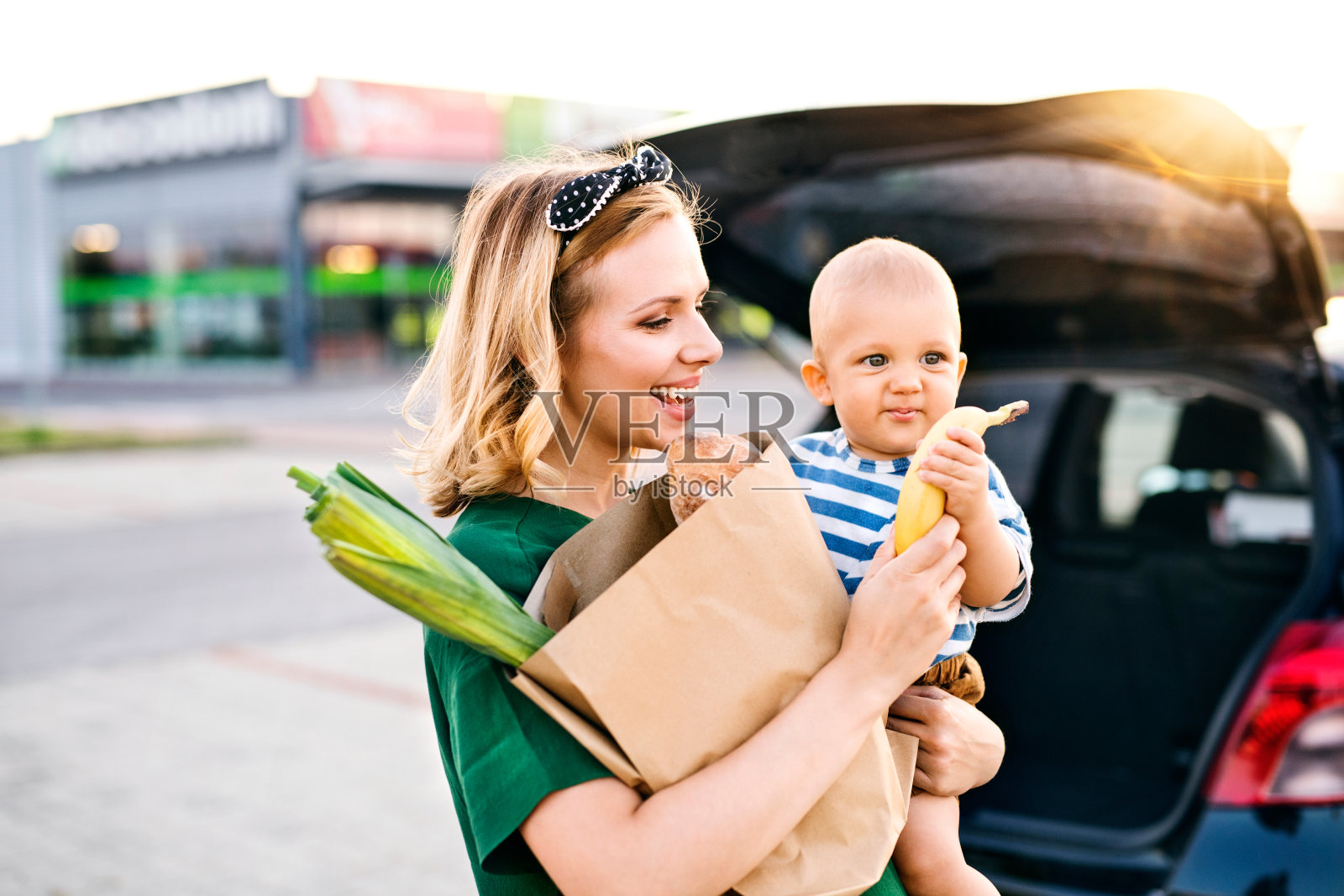 年轻的母亲带着儿子站在超市前。照片摄影图片