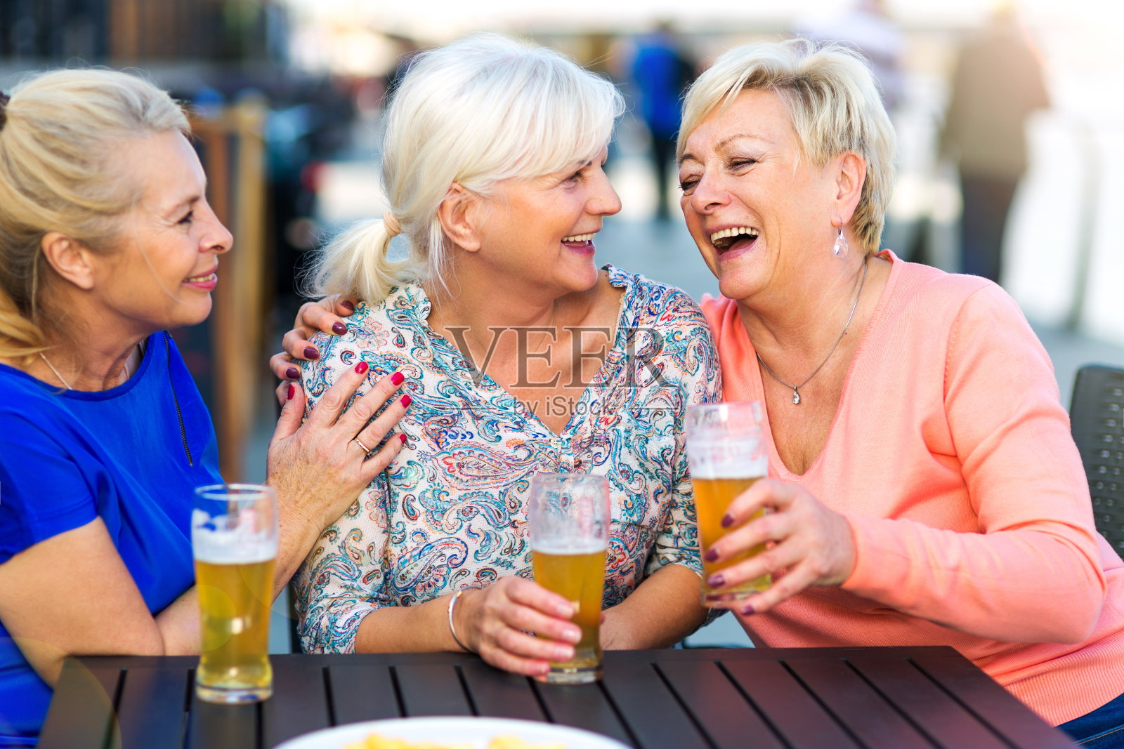 微笑的老年妇女在一个户外酒吧喝啤酒照片摄影图片