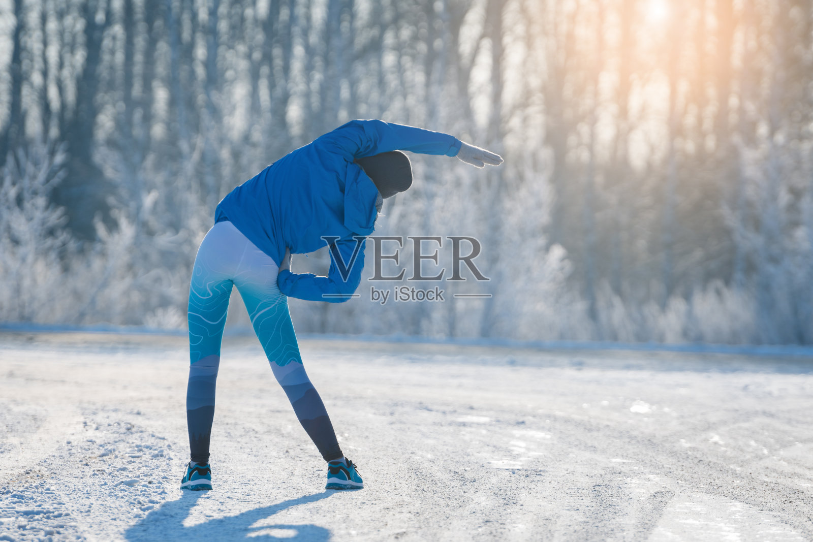 跑步者在冬季公园伸展。健康的生活方式。照片摄影图片