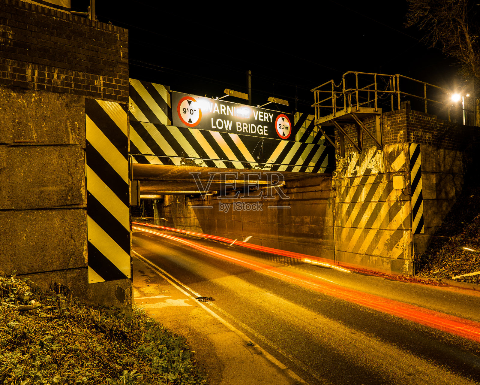 低桥，夜间有警告标志照片摄影图片