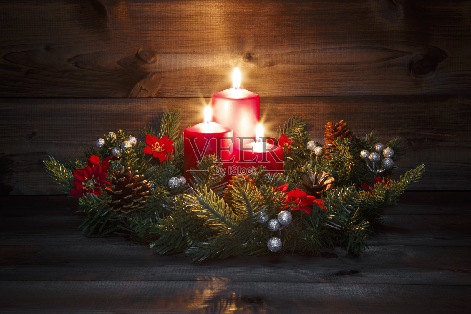 第三个降临节-装饰的降临节花环与三个红色燃烧的蜡烛在木质的背景与节日气氛照片摄影图片