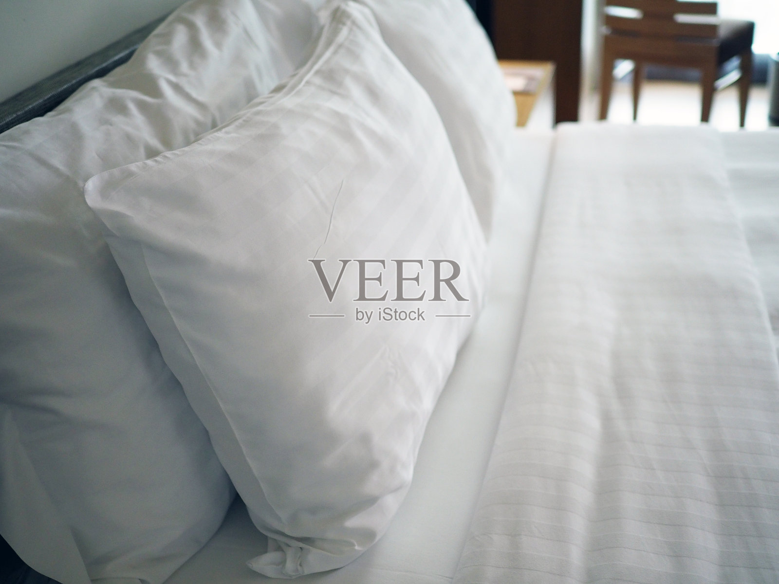 又大又软的白色枕头，豪华舒适的白色床上还有干净的白色床单。健康睡眠，深度放松和舒适的理念。照片摄影图片