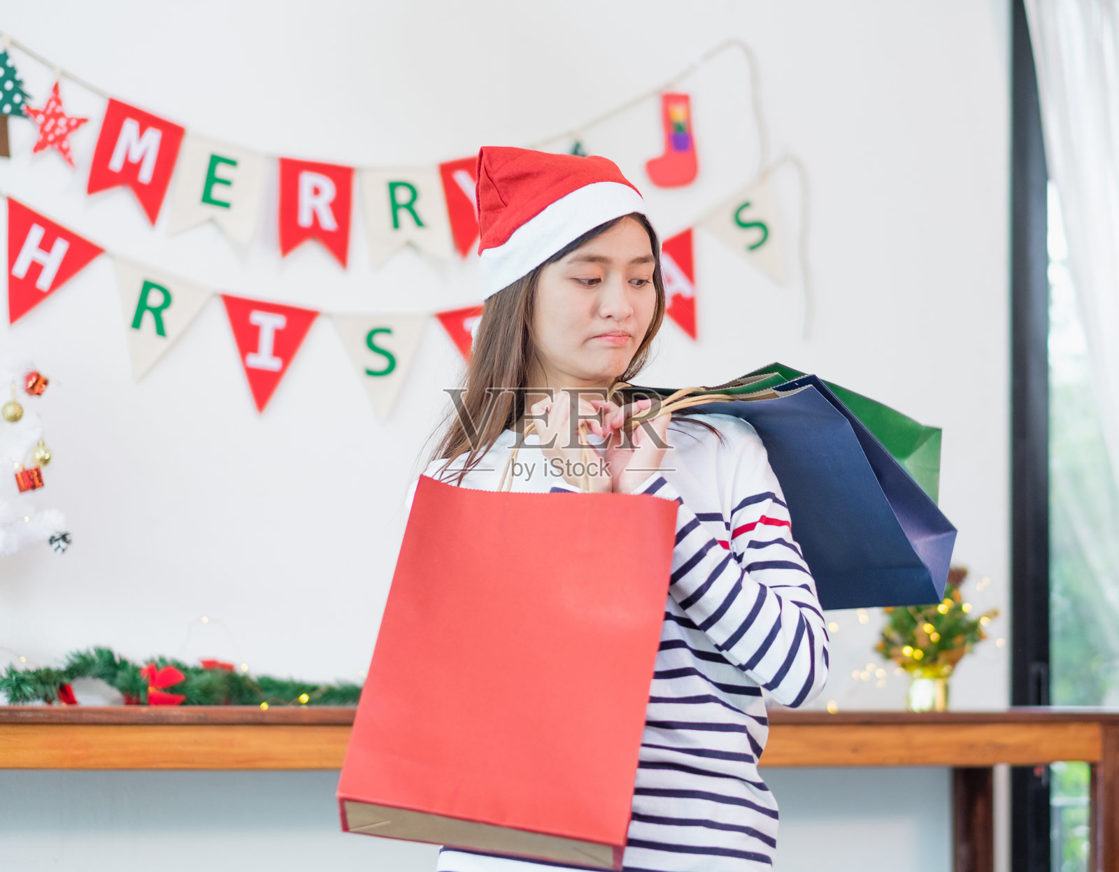 亚洲女人失望付款时买了很多圣诞礼物在购物袋，心烦费用后购物时间，不开心的女孩可怜购物狂，超支，花了所有的钱在假期。照片摄影图片