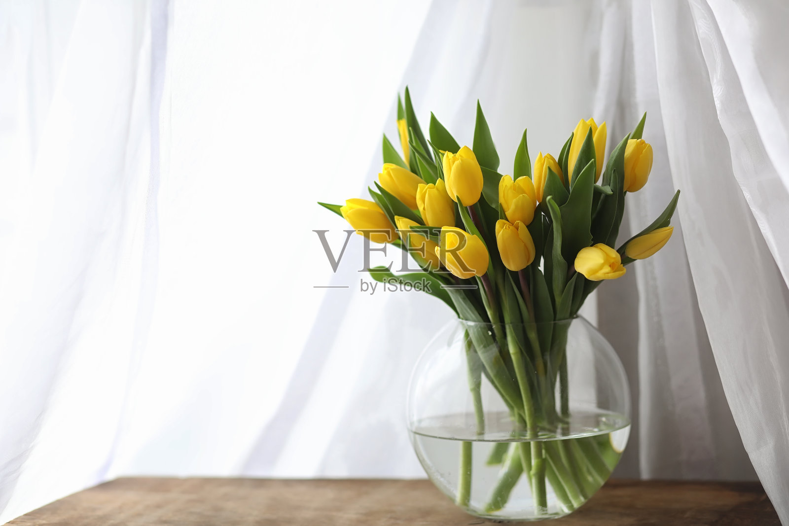 窗台上的花瓶里插着一束黄色郁金香。一份礼物t照片摄影图片