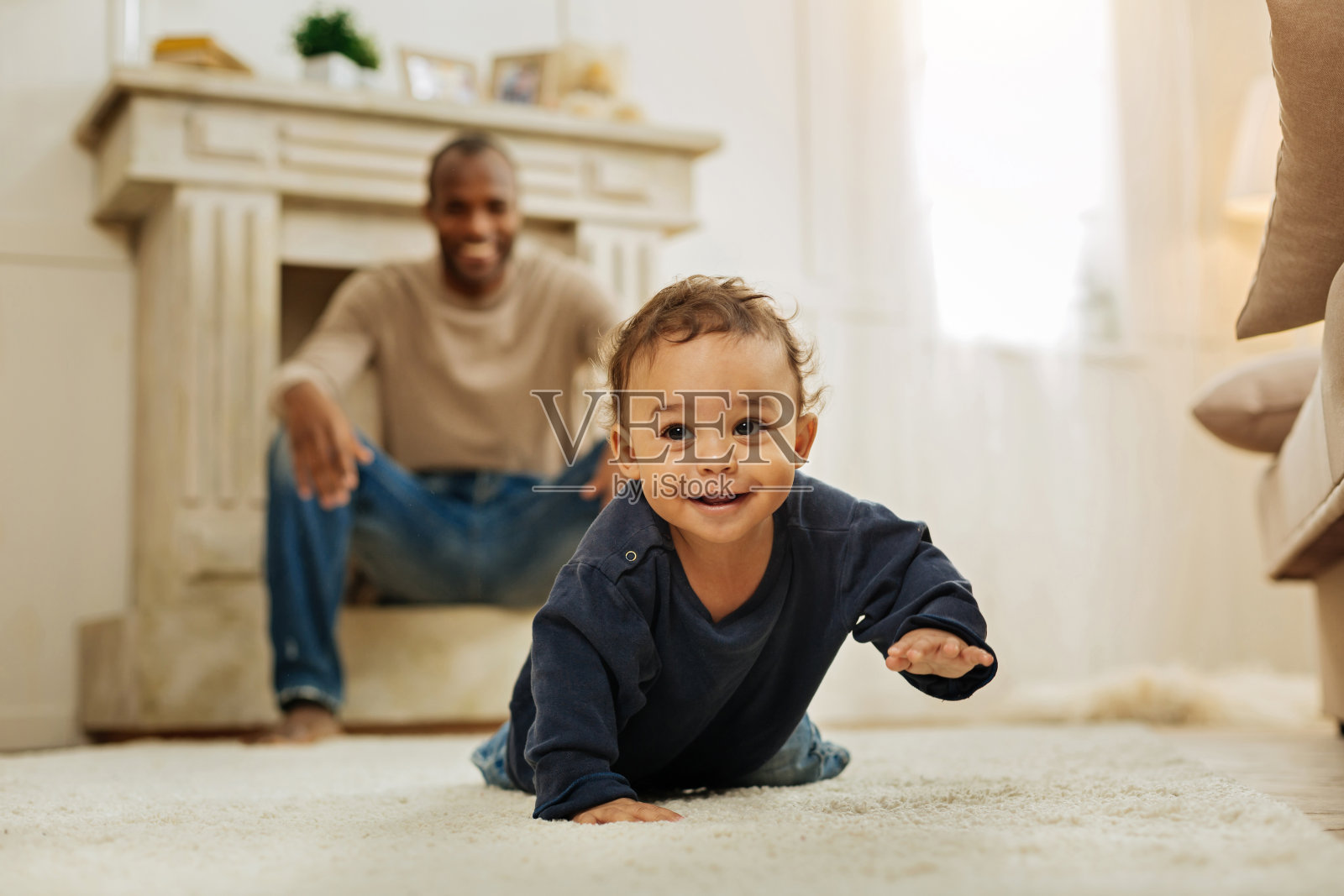 微笑的父亲看着他的儿子爬照片摄影图片