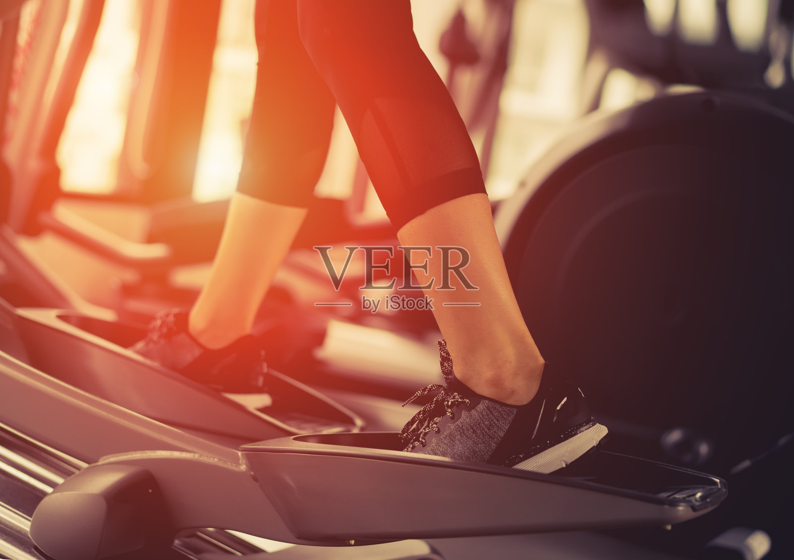 早晨在健身馆椭圆有氧跑步锻炼，以机器有氧减肥的女性为苗条而坚定的健康生活方式。照片摄影图片