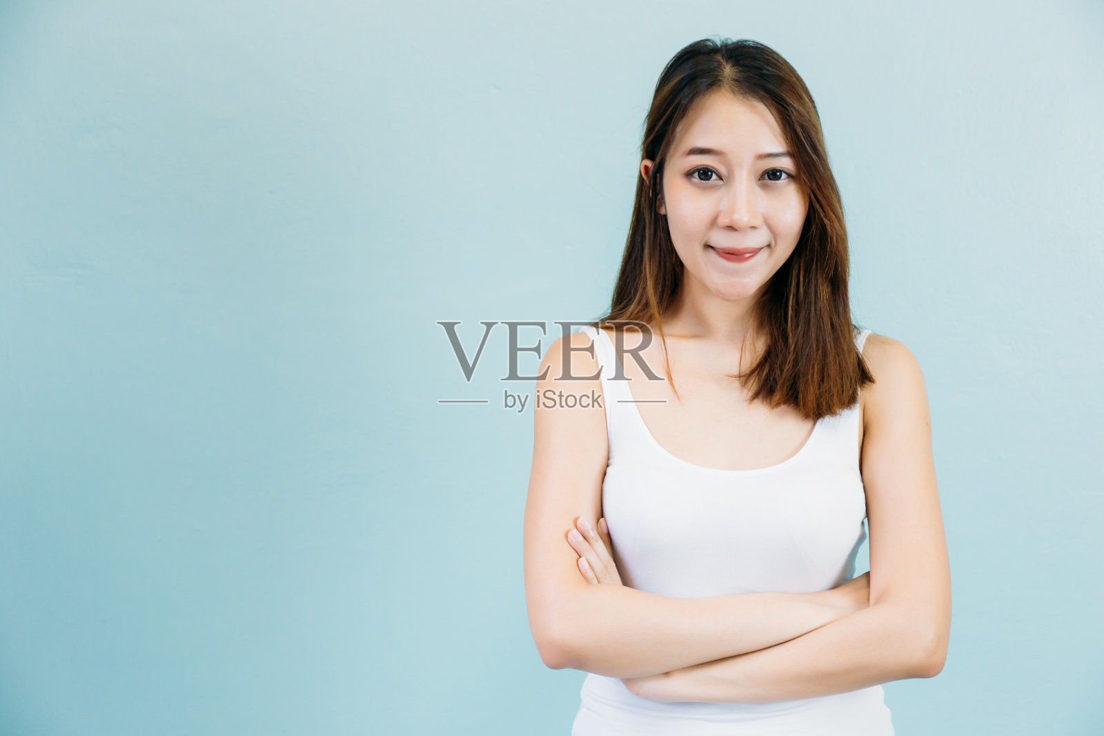 迷人的亚洲女人微笑和双臂交叉孤立在蓝色柔和的背景照片摄影图片