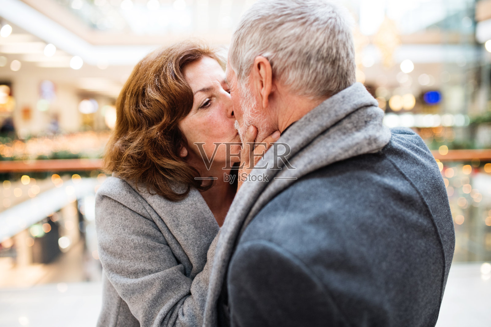 老夫妇在采购圣诞礼物，接吻。照片摄影图片