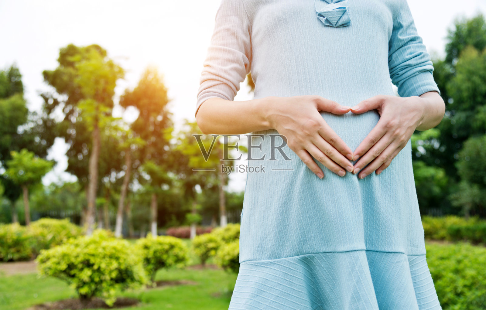 一个孕妇在肚子上摆出心形的姿势照片摄影图片