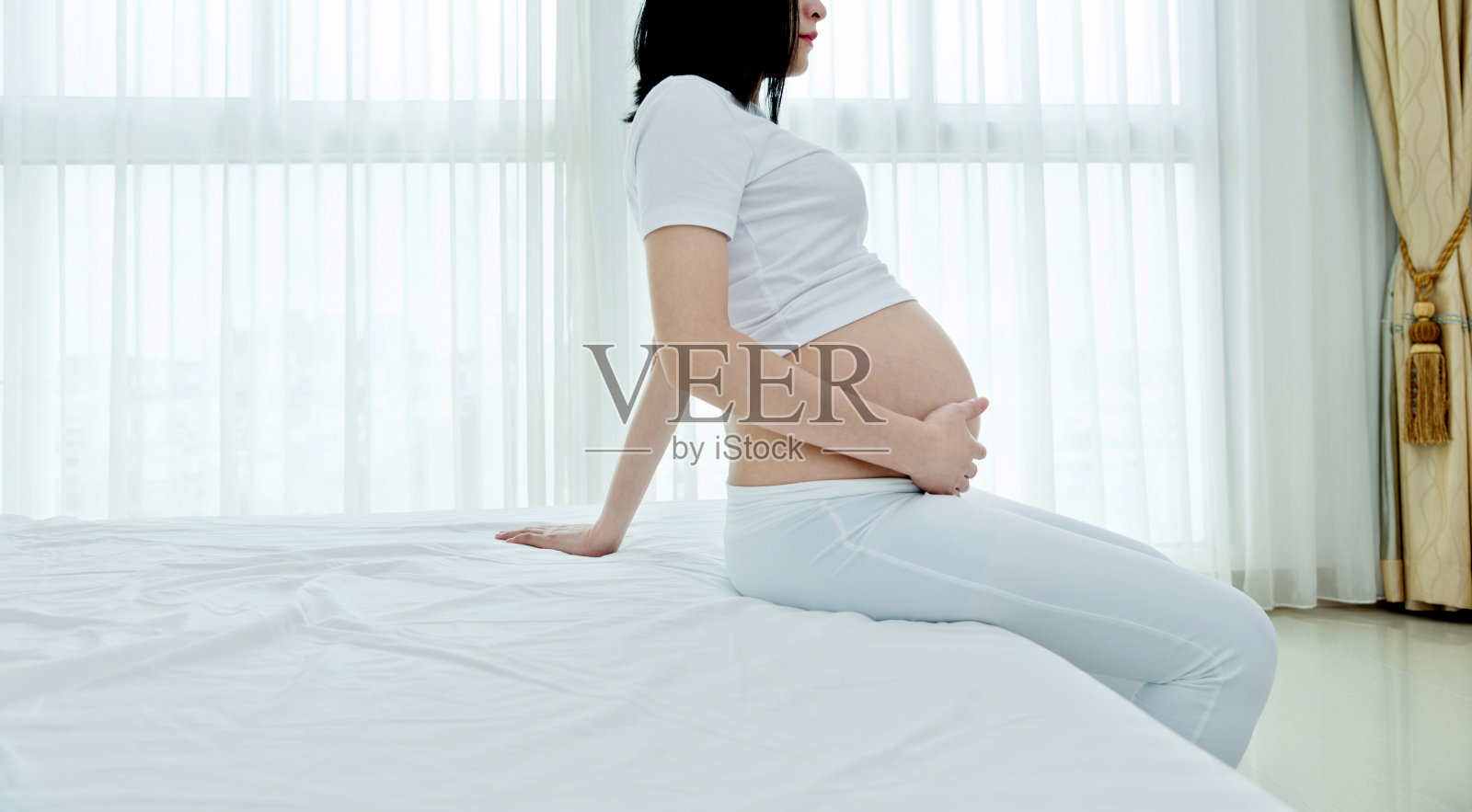 一个孕妇坐在床边照片摄影图片
