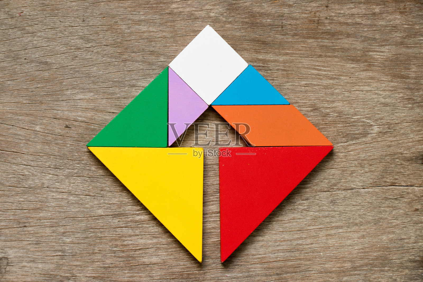 色彩缤纷的七巧板拼图在方形与内箭头方向形状上的木材背景照片摄影图片