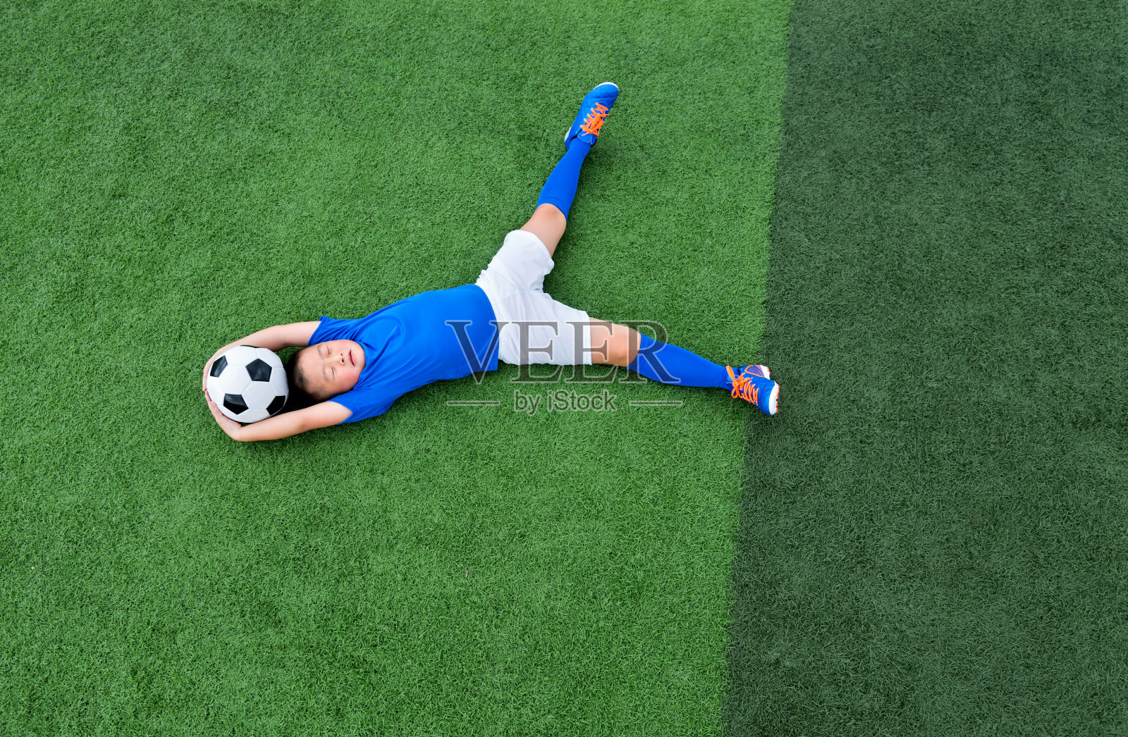 小男孩躺在足球场上照片摄影图片