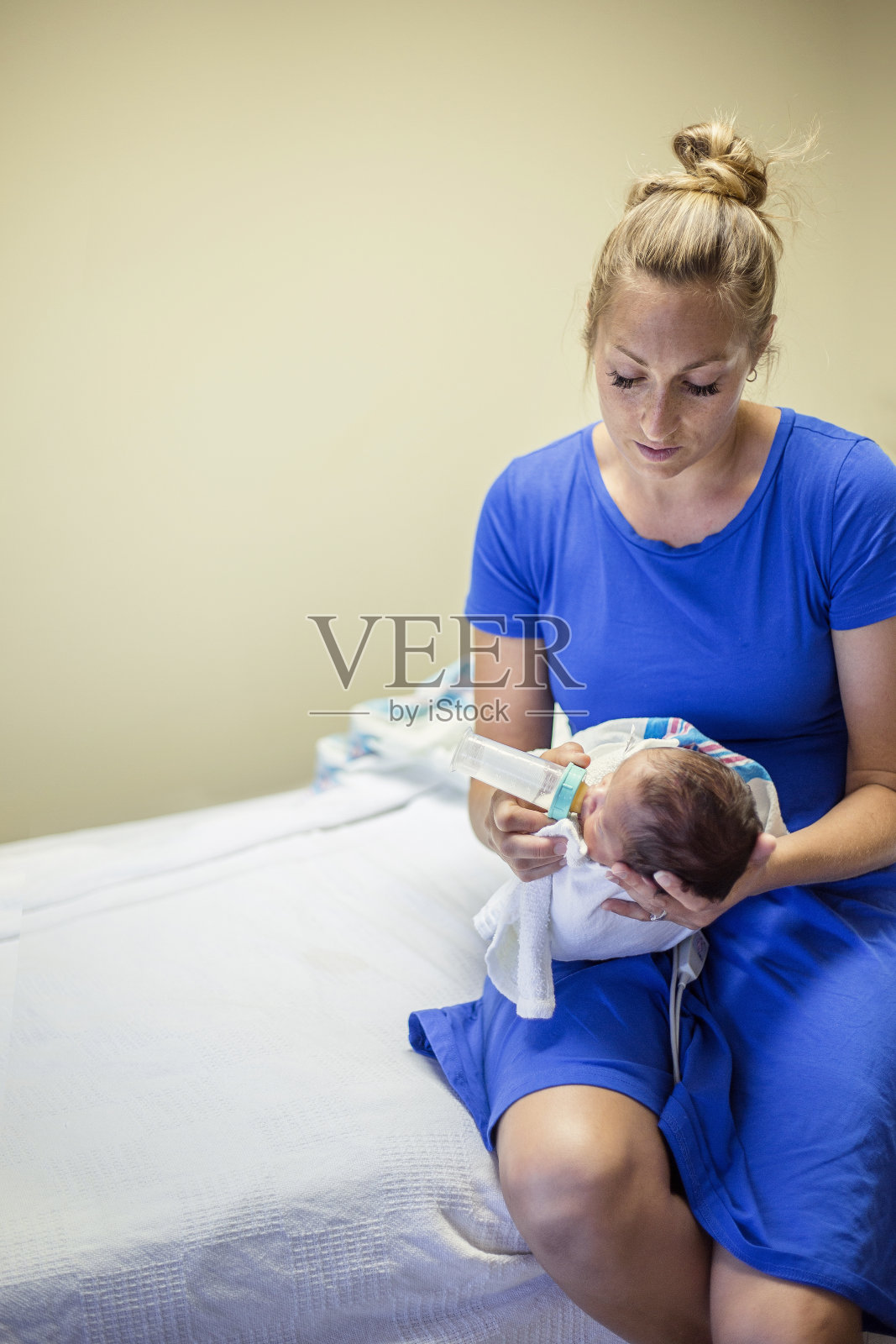 年轻的母亲用奶瓶喂她刚出生的男婴照片摄影图片