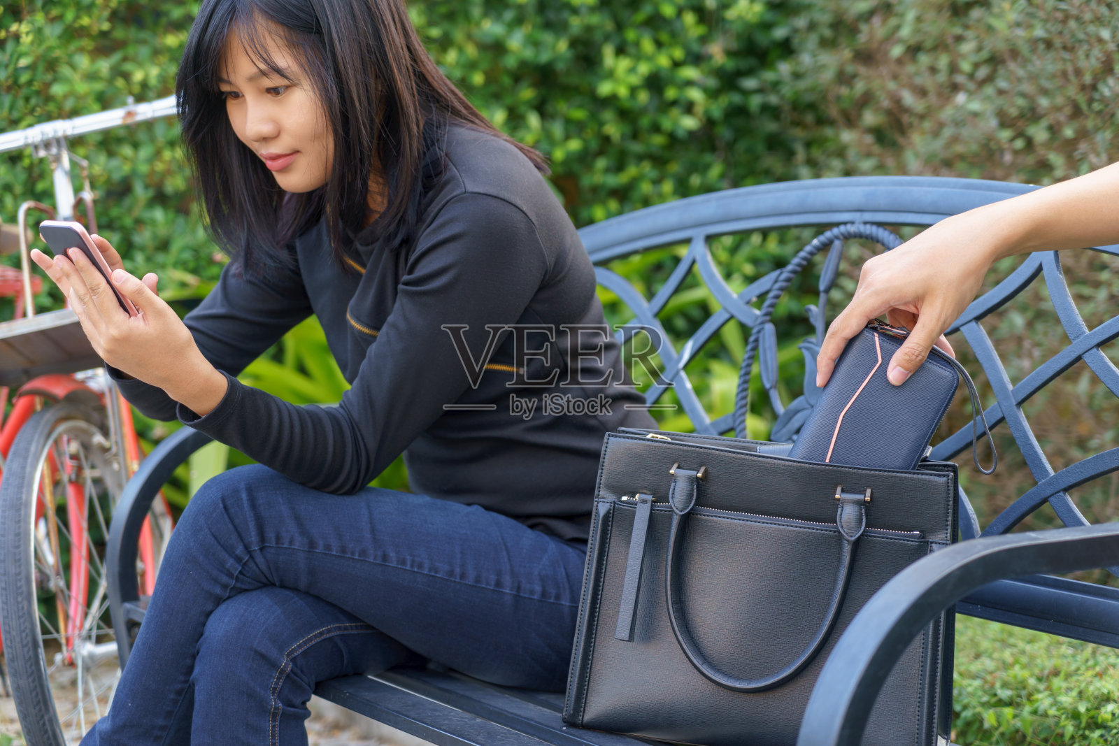 小偷试图偷走钱包，而妇女使用手机和坐在椅子上。照片摄影图片