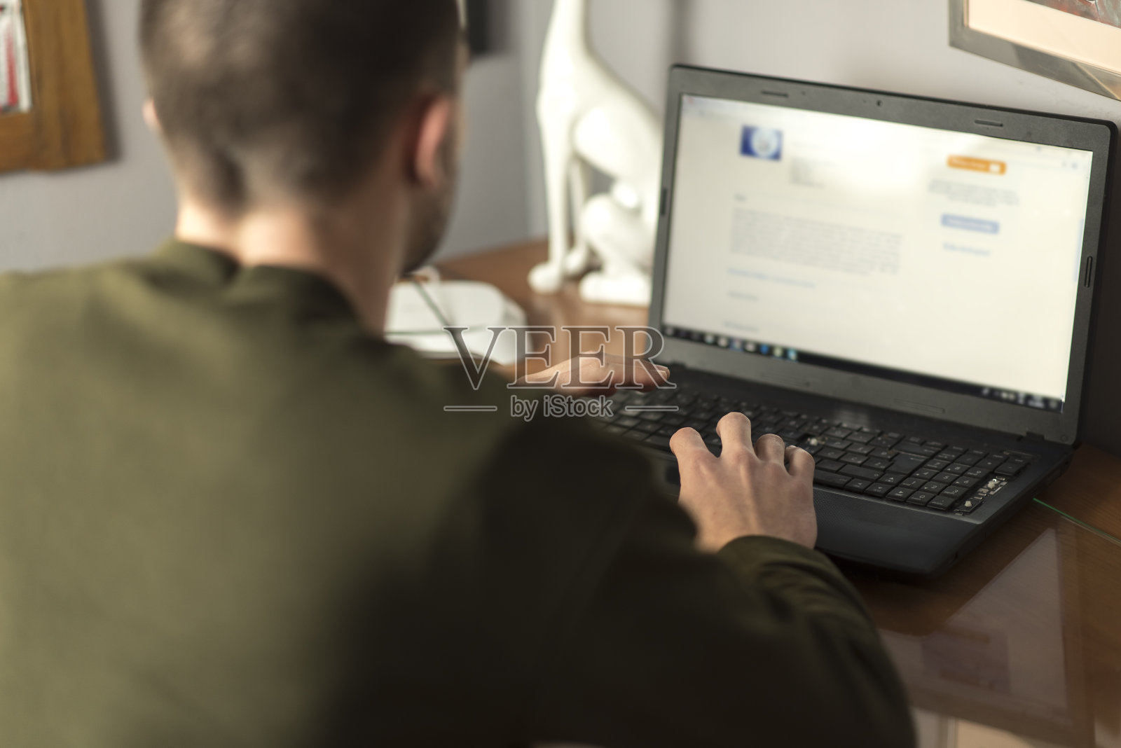 一个年轻人在他的自习室里使用笔记本电脑，裁剪和近距离照片摄影图片