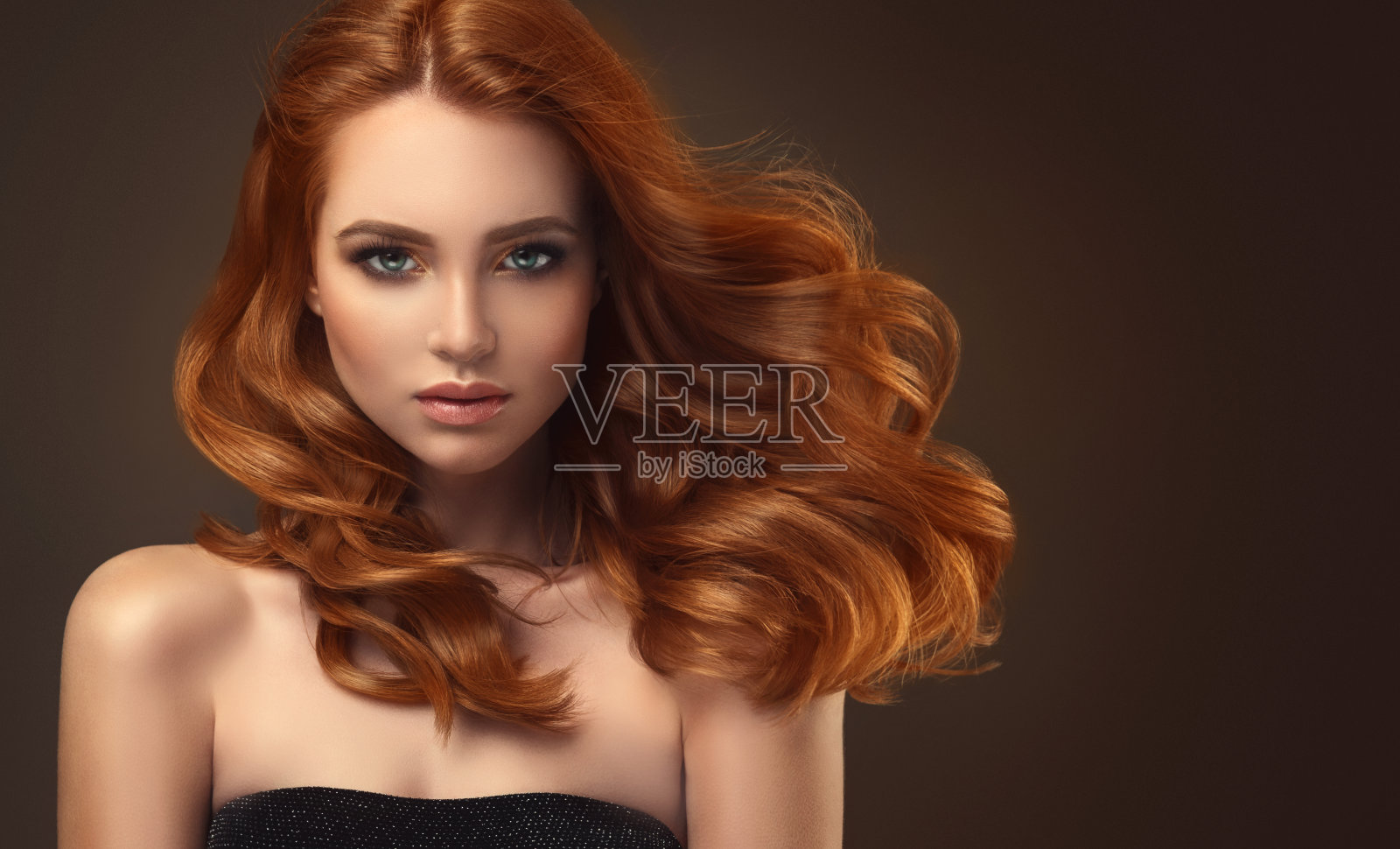 红头发的女人，有着丰满的，有光泽的和卷曲的发型。飞行的头发。照片摄影图片