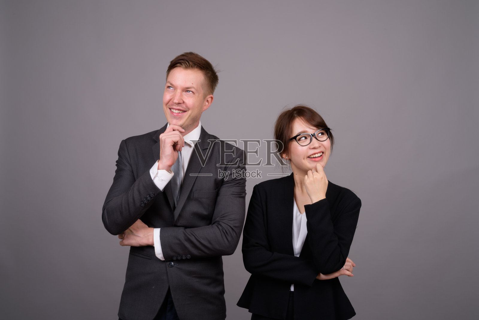 工作室拍摄的年轻英俊的商人和年轻美丽的亚洲女商人在灰色的背景照片摄影图片