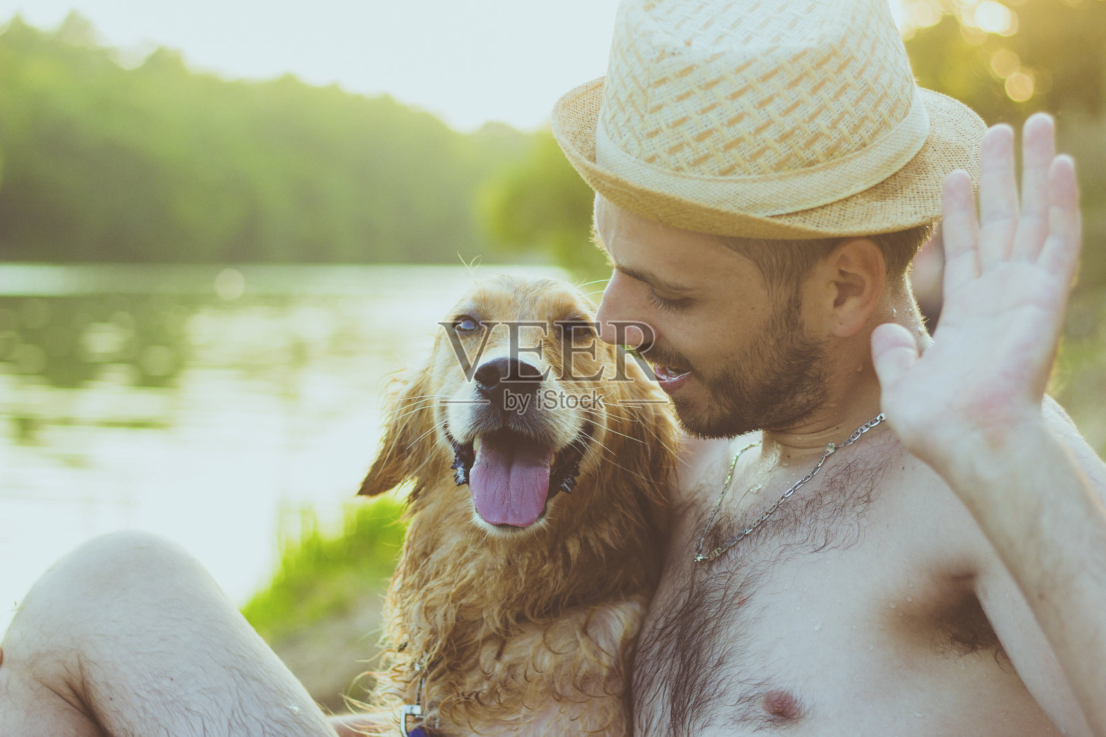 友谊的概念，人和金毛猎犬一起坐在沙滩上照片摄影图片