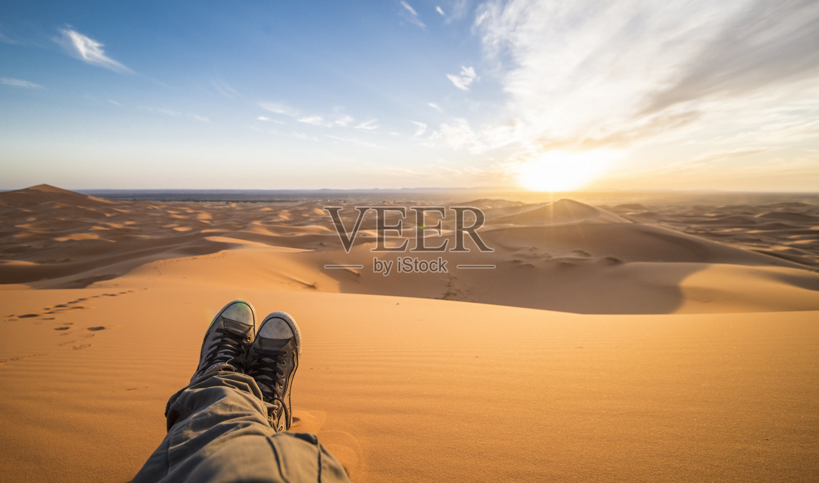 一个男人在撒哈拉沙漠- Merzouga -摩洛哥的沙丘上欣赏日落照片摄影图片