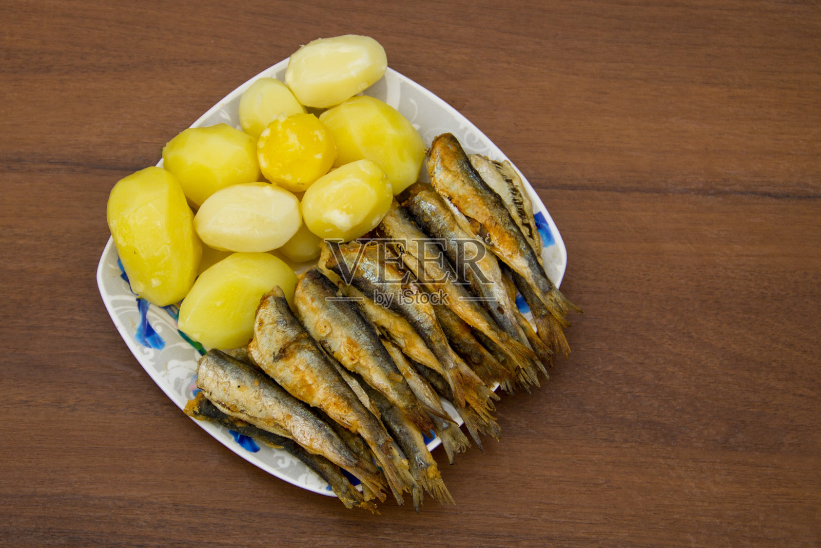 以木为背景的盘子上，炒波罗的海鲱鱼配煮土豆照片摄影图片