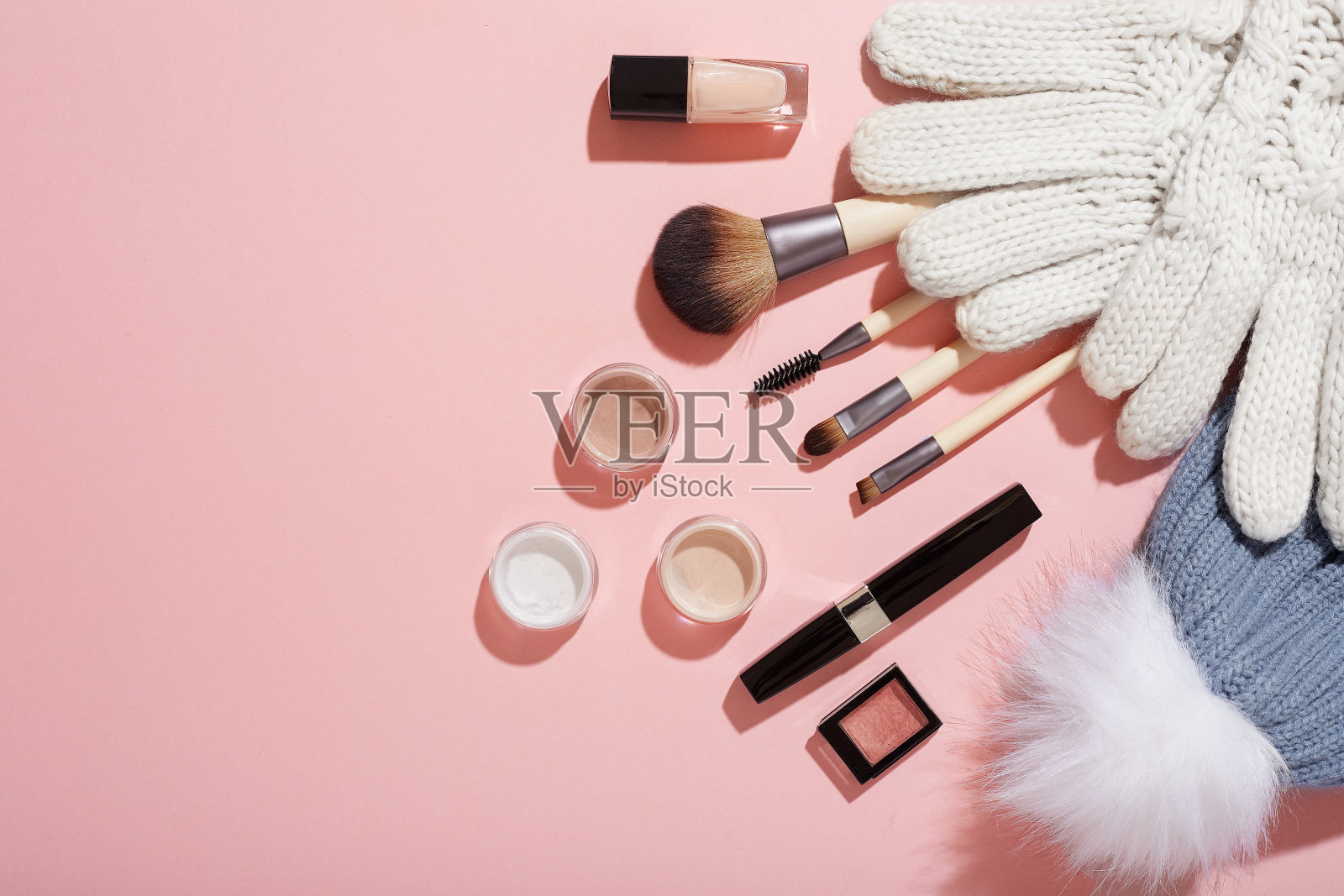冬天的妆，粉色背景的手套和绒球帽照片摄影图片