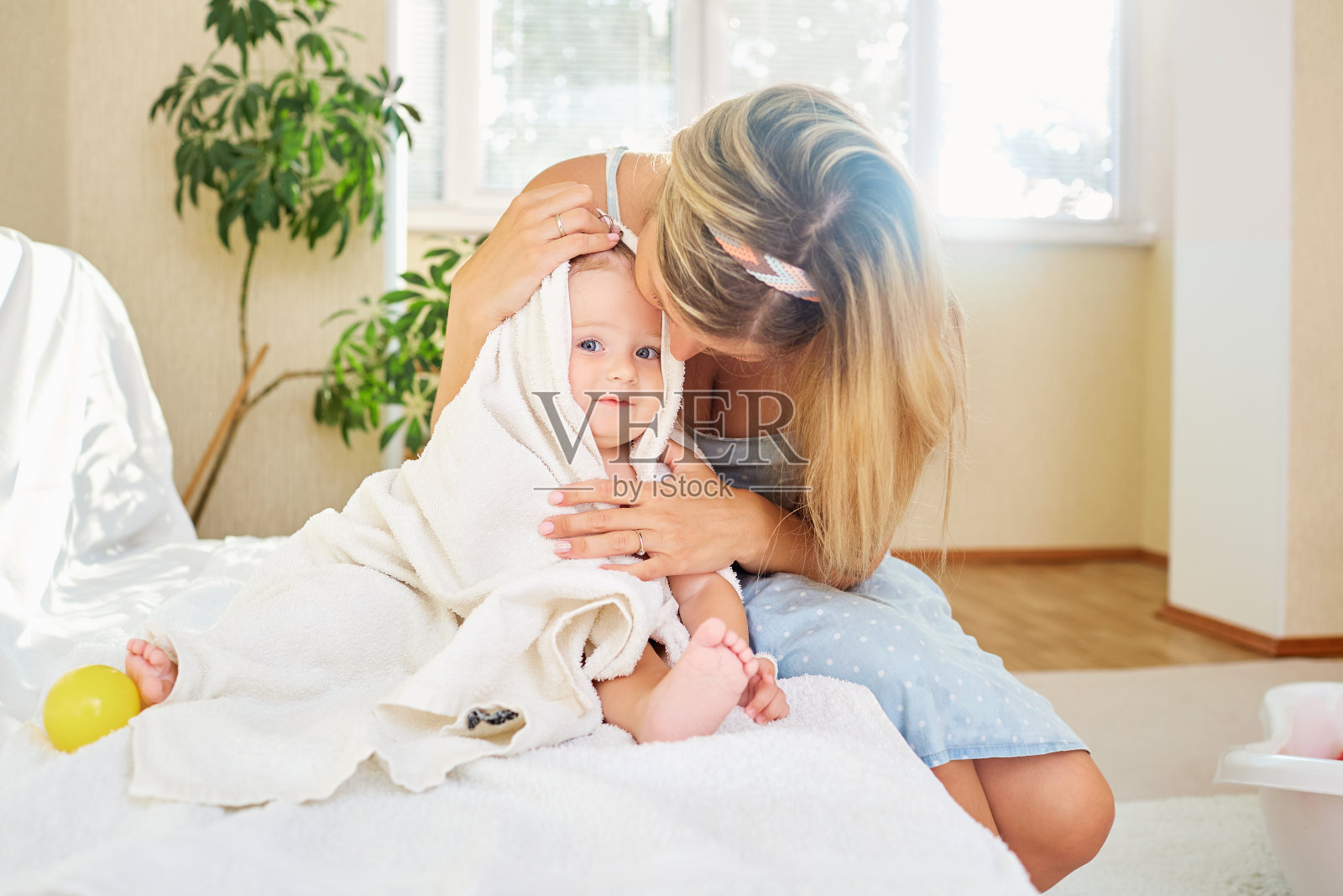 一位母亲在房间内的毛巾间拥抱她的婴儿照片摄影图片